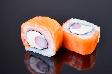 Philadelphia roll sushi with salmon, crab sticks and cream cheese on black background for menu. Japanese food