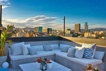 The white cosy sofa on an outdoor rooftop terrace with an amazing view on Barcelona downtown