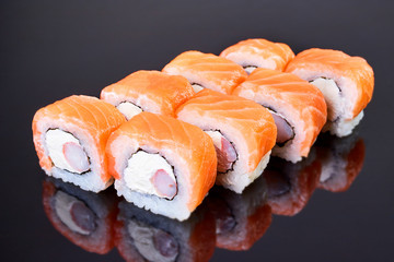 Philadelphia roll sushi with salmon, crab sticks and cream cheese on black background for menu. Japanese food