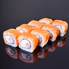 Philadelphia roll sushi with salmon, crab sticks and cream cheese on black background for menu. Japanese food
