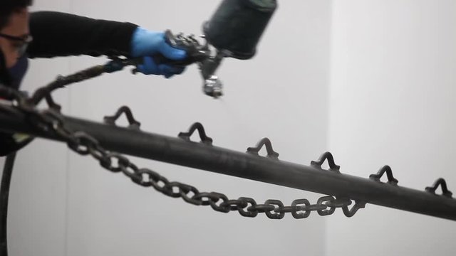 Professional air brusher working in a spray booth on metal parts 2