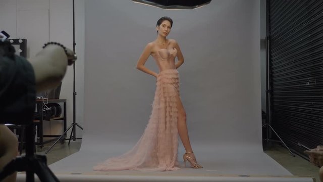Model woman in pink dress posing for photographer in studio, Wide Shot