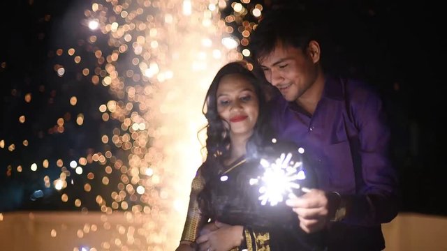 Young Couple Holding Fire Sparkle Cracker And Celebrating New Year Or Diwali At Night, Slomotion.