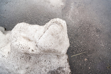 Dirty snow on the background of wet asphalt
