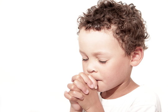 little boy praying to God stock image with hands held together with closed eyes  stock photo