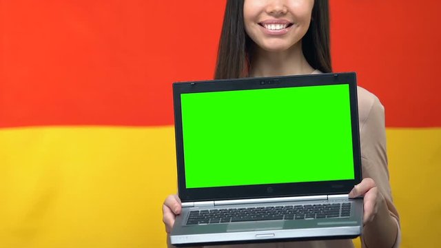 Laptop with green screen in womans hands, German flag background, traveling app