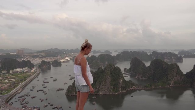 Blonde tourist girl looking over the bay in Ha Long from the top of Poem Mountain in Vietnam