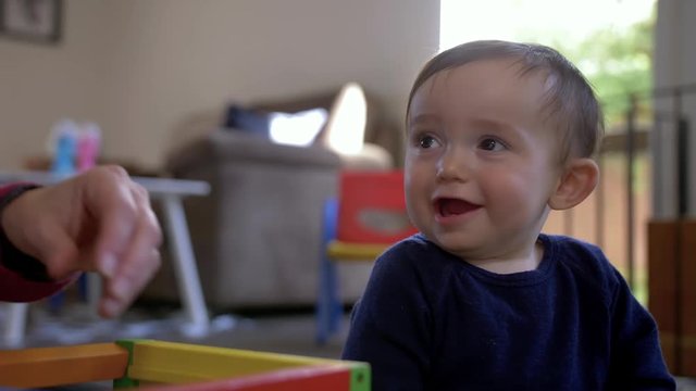 Shot of a cute baby boy laughing and smiling as a hand comes in and out of the frame