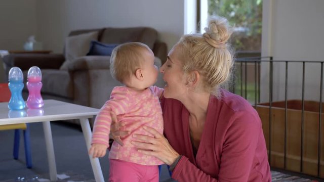 Slow motion shot of a young woman holding and kissing an energetic baby girl