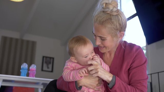 Slow motion shot of a blonde haired lady playing with her baby daughter