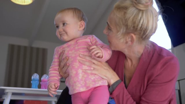Shot of a blonde haired mother holding her baby girl as she tries to walk