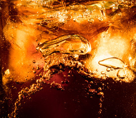 Close up view of the ice cubes in dark cola background. Texture of cooling sweet summer's drink with foam and macro bubbles on the glass wall. Fizzing or floating up to top of surface.