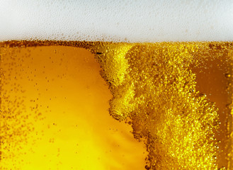 Close up view of floating bubbles in light golden colored beer background. Texture of cooling...