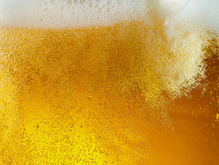 Close up view of floating bubbles in light golden colored beer background. Texture of cooling summer's filtered drink with foam and macro fizz on the glass wall. Fizzing or floating up to top of - obrazy, fototapety, plakaty