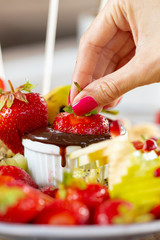 Dipping of tasty strawberry into bowl with chocolate