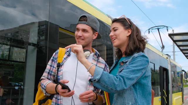 Smiling girl helping lost male tourist to find way. Lost tourist to find way. Background tram station.