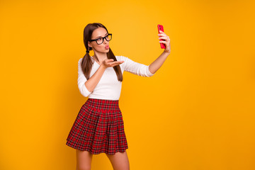 Portrait of nice-looking attractive lovely lovable tender winsome girl holding in hand camera making taking selfie video message isolated on bright vivid shine yellow background