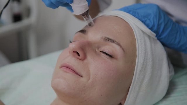 Professional cosmetologist performs DermaPen procedure in a cosmetology clinic.
