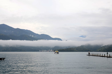 Cloudy evening of Sun Moon Lake. A boat sailing to the pier.