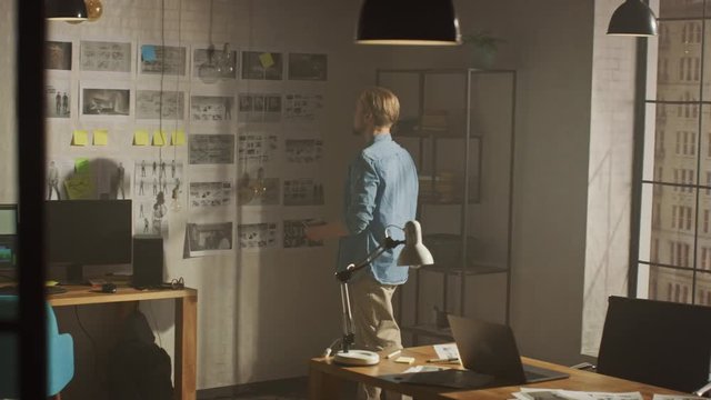 Young Creative Designer Looks at the Storyboard Sketches Covering his Wall, He Chooses Between Concept Drawings, Wondering How to Proceed with this Important Story for His Video Gaming Project