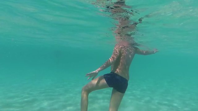 Young kid learning to swim in blue sea water during summer beach vacations. 