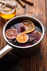 Mulled wine hot drink with citrus, apple and spices in aluminum casserole and Fir branch on background.