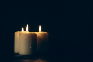 candles burning in darkness over black background. commemoration concept.