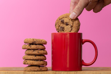 Dunking a biscuit in to a cup of coffee or tea - obrazy, fototapety, plakaty