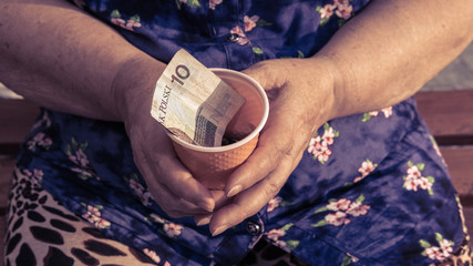 Old woman begs for alms. Closeup of money and coins in hand of poor woman.