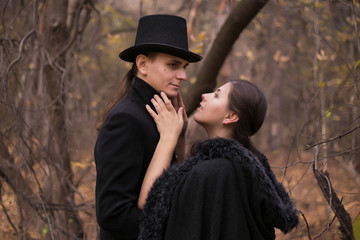 Fototapeta premium A woman and a man in nineteenth-century clothes in a gloomy forest. Man hugging a woman close up