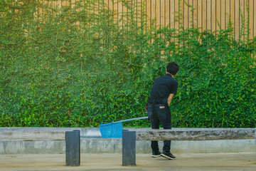 Fototapeta premium Young man cleaning fountain pool from fallen leaves with net .