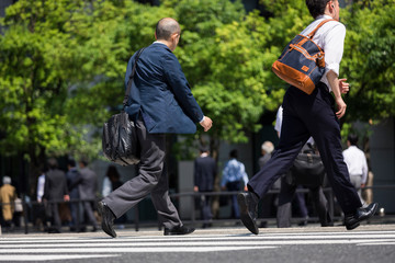 走って横断歩道を渡るビジネスマンの後ろ姿