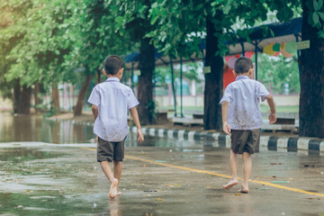 Boy students leave the classroom to walk on the street after heavy rain in the school.