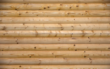 Wall of planed wooden logs.