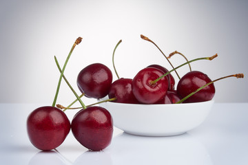 ripe red cherries in a cup on a bright glossy background