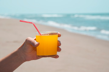 man having an orange drink on the beach.