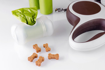 walking equipment, poop bags with leash and dog treats on white background