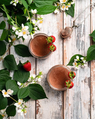 chocolate dessert in a jar decorated with strawberries on a wooden backdrop, blossomed flowers,