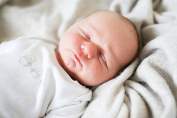 Newborn baby boy sleeping in children's cot - closeup