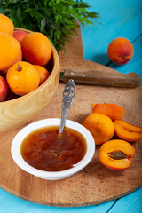 Apricot jam and fresh apricots in wood bowl. 