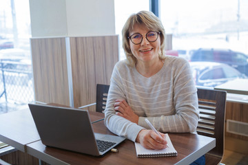 middle-aged woman business in workplace in cafe, office, she's working on her laptop.