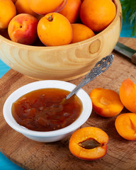 Apricot jam and fresh apricots in wood bowl. 