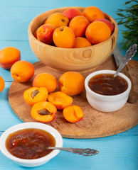 Apricot jam and fresh apricots in wood bowl. 