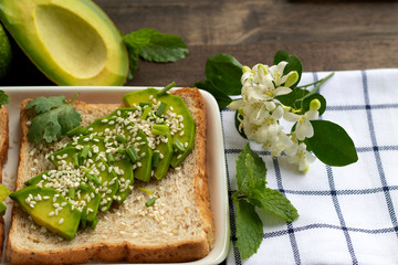 fresh avocado with whole wheat bread and sesame in dish on wood background