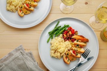 Delicious meal made of chicken fillet, green beans, mashed potato and vegetable sauce with white wine on a wooden table. Top view, above shot.