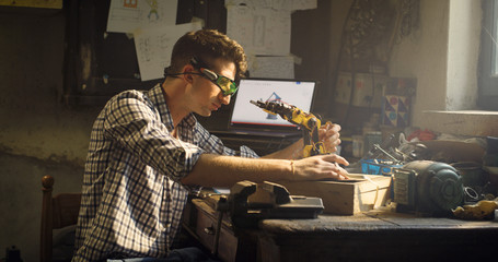 Portrait of an young professional engineer with specific glasses is working on projection of an innovative technology mechanical arm in his workshop.