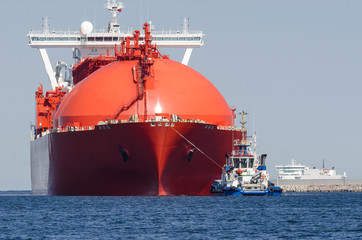 RED LNG TANKER - The big ship maneuvers in the mooring port at the wharf