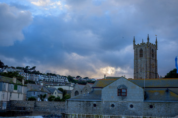 St Ives City during sunset. St Ives is a seaside town, civil parish and port in Cornwall, UK. The town lies north of Penzance and west of Camborne on the coast of the Celtic Sea