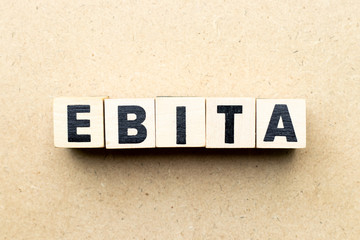 Obraz premium Alphabet letter block in word EBITA (abbreviation of earnings before interest, taxes and amortization) on wood background