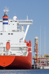 LNG TERMINAL AND GAS CARRIER - A large red ship moored to the wharf